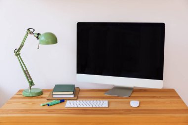 Ev çalışma alanı. Modern bilgisayar, lamba ve kırtasiye malzemeleri ahşap masa içinde.