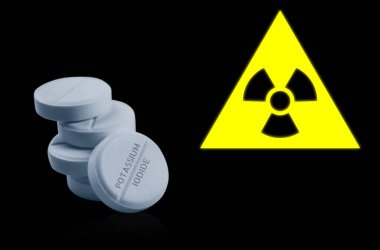 Potasyum iyodür hapları ve siyah arka planda uyarı işareti. Radyoaktif kirlenme sırasında iyot tüketimi