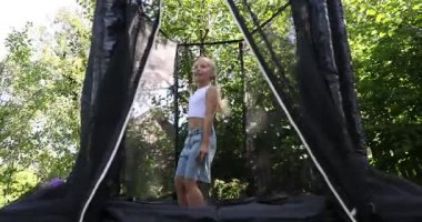 Dışarıda siyah trambolinde zıplayan mutlu küçük kız.