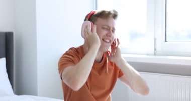 Mutlu adam kulaklıkla müzik dinliyor ve evde dans ediyor.