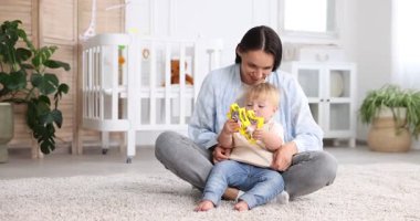 Anne ve küçük tatlı çocuğu bebek odasında oyuncaklarla oynuyorlar.