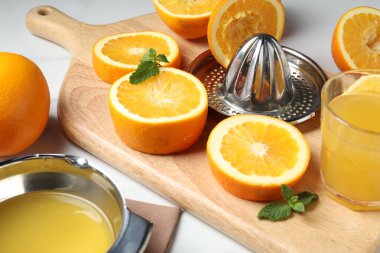 Sıkılmış portakallar meyve sıkacağı ve bir bardak meyve suyu, ahşap masa, yakın plan.