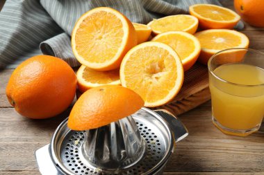 Taze sıkılmış portakal suyu, meyve suyu ve meyve sıkacağı ahşap masada, yakın plan.