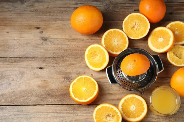 Taze sıkılmış portakal suyu, meyve suyu ve meyve sıkacağı ahşap masada, düz yerde. Metin için boşluk