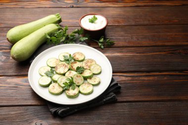 Ahşap masada servis edilen maydanozlu lezzetli kızarmış kabak dilimleri, yakın plan. Metin için boşluk