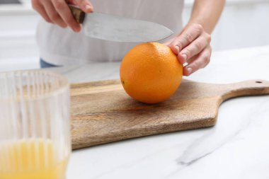 Meyve suyu. Beyaz mermer masada turuncu kesen kadın, yakın plan.