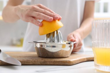 Meyve suyu. İçerideki beyaz mermer masada portakal suyu kullanan kadın, yakın plan.