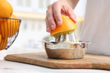 Meyve suyu. İçerideki beyaz mermer masada portakal suyu kullanan kadın, yakın plan.