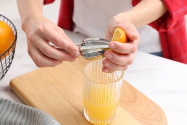 Meyve suyu. İçerideki beyaz mermer masada portakal suyu kullanan kadın, yakın plan.
