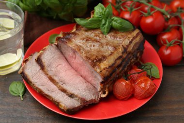 Lezzetli pişmiş et, domates, fesleğen ve ferahlatıcı içecek ahşap masada, yakın plan.