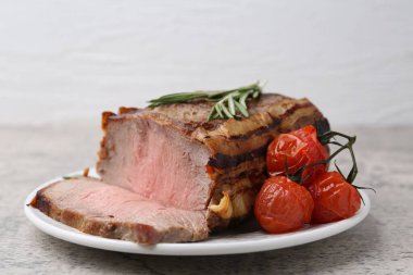 Lezzetli pişmiş et, domates ve biberiye gri masada, yakın plan.