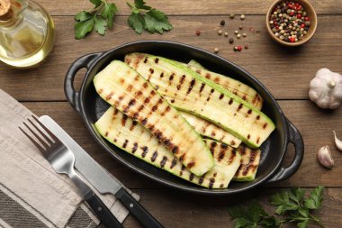 Lezzetli ızgara kabak dilimleri, ahşap masa üzerinde yağ ve baharatlar, düz uzanma