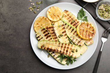 Gri desenli masada servis edilen balkabağı tohumlu, limonlu ve maydanozlu lezzetli kabak dilimleri.