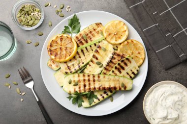 Gri desenli masada servis edilen balkabağı tohumlu, limonlu ve maydanozlu lezzetli kabak dilimleri.