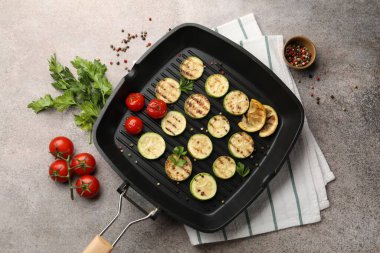 Lezzetli ızgara kabak dilimleri domatesli, limonlu ve maydanozlu tavada gri desenli masa, düz uzanmış