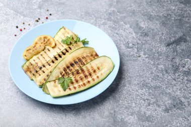 Lezzetli ızgara kabak dilimleri, maydanozlu ve limonlu gri desenli masa, yakın plan. Metin için boşluk