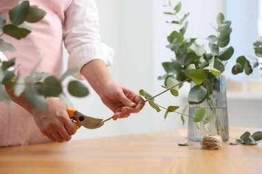 Çiçekçinin ahşap masasında okaliptüs dallarından güzel bir buket yapıyor.