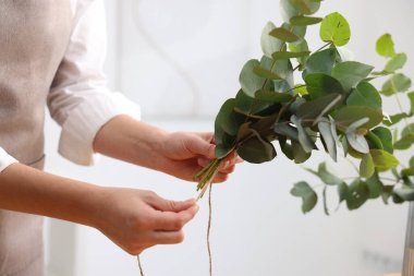 Çiçekçi, çiçekçide okaliptüs dallarından güzel bir buket yapıyor.