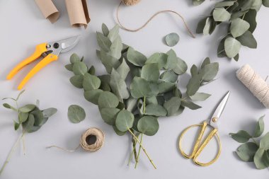Çiçekçi. Okaliptüs dalları, iplikler, budama, kağıt ve makas beyaz masaya, düz yatıyordu