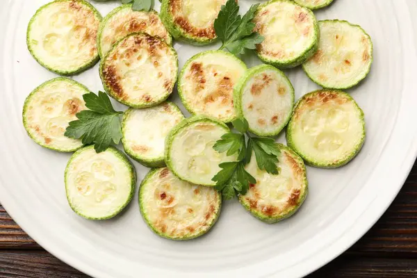 Ahşap masada maydanozlu lezzetli kızarmış kabak dilimleri.