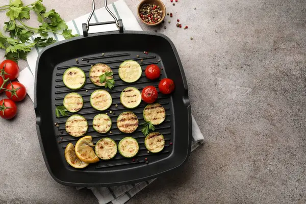 Lezzetli ızgara kabak dilimleri, domatesli, limonlu ve maydanozlu tavada gri desenli masa, düz yatak. Metin için boşluk