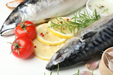Beyaz masada taze çiğ uskumrular ve baharatlar, yakın plan. Deniz ürünleri lezzetleri.