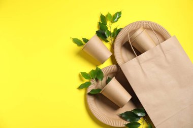 Farklı çevre dostu ambalajlar, sofra takımı ve sarı arka planda yapraklar, düz yatış. Metin için boşluk