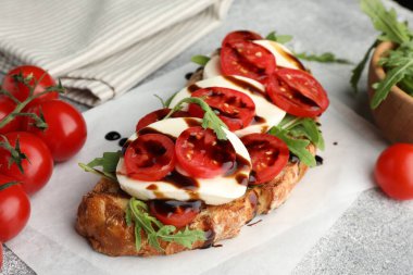 Mozarella peynirli lezzetli sandviç, balzamik sos, domates ve roka gri masada, yakın plan.