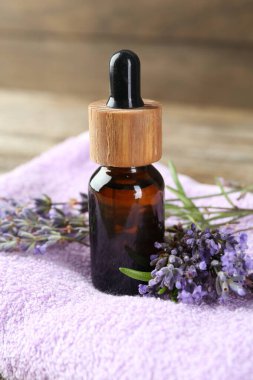 Lavanta yağı, çiçekler ve havlu ahşap masada, yakın plan.