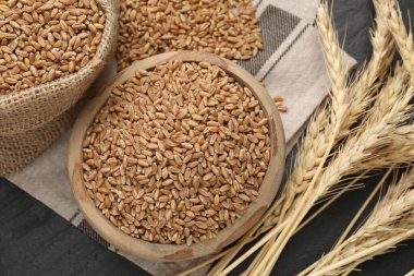 Kasede buğday taneleri, çuval bezi torbası ve siyah masada çiviler.