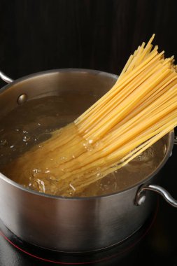 Taze tagliatelle makarnası tencerede kaynar su ve elektrikli soba, yakın plan.