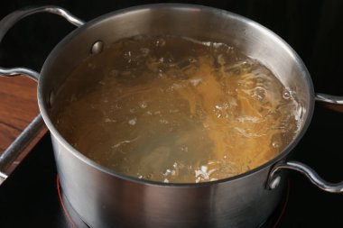 Taze tagliatelle makarnası tencerede kaynar su ve elektrikli soba, yakın plan.