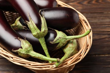Tahta masada sepetin içinde bir sürü olgun patlıcan var.