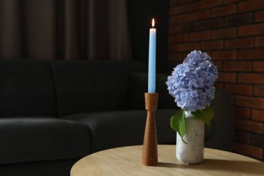 Evdeki ahşap masada yanan mum ve ortanca çiçekleri. Metin için boşluk
