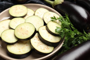 Taze patlıcan dilimleri, bütün olanlar ve maydanozlar masada, yakın plan.