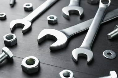 Birçok metal anahtar, cıvata ve somun siyah ahşap masa, yakın plan