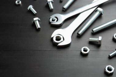 Siyah ahşap masanın üstünde birçok metal anahtar, cıvata ve ceviz var. Metin için boşluk