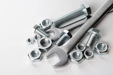 Beyaz arka planda birçok metal anahtar, cıvata ve fındık var.