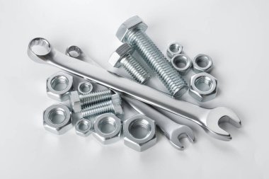 Beyaz arka planda birçok metal anahtar, cıvata ve fındık var.