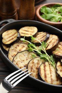 Izgara patlıcan dilimleri ve mikroyeşillikler ahşap masada servis edilir, yakın plan.