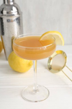 Bardakta limon dilimli martini kokteyli, beyaz ahşap masada meyve ve sallama, yakın plan.