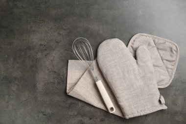 Gri fırın eldiveni, tutacağı, havlu ve çırpılmış koyu desenli masa, düz yatak. Metin için boşluk