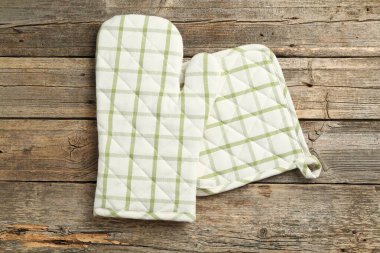 Fırın eldiveni ve tutacağı ahşap masanın üstünde, üst tarafta.