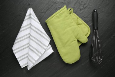 Yeşil fırın eldiveni, havlu, tutucu ve koyu desenli masa üzerinde çırpma, düz uzanma