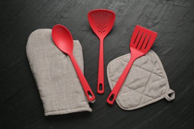 Gri fırın eldiveni ve diğer mutfak gereçleri koyu dokulu masa üzerinde, düz yatıyordu.