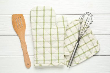 Fırın eldiveni, tutucu, çırpıcı ve spatula beyaz ahşap masa, düz yatıyordu.