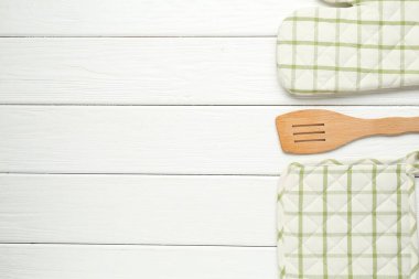 Fırın eldiveni, tutacağı ve beyaz ahşap masa üzerinde spatula, düz yatak. Metin için boşluk