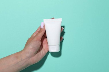 Turkuaz arka planda kozmetik ürünü olan bir kadın, yakın plan. Tasarım için model