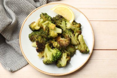 Lezzetli kızarmış brokoli ve limon açık ahşap masada.