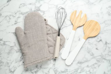 Fırın eldiveni, tutkal ve diğer mutfak gereçleri beyaz mermer masa, düz yatıyordu.